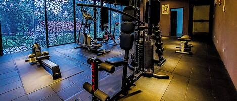 Ein Fitnessstudio mit verschiedenen Trainingsgeräten, darunter ein Squat-Gestell und Kurzhanteln.