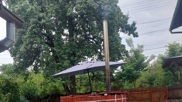 Un patio trasero con jacuzzi, terraza de madera, hamaca y una mesita.