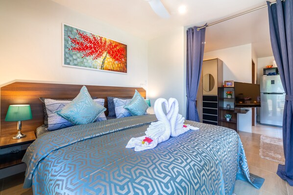Una habitación de hotel moderna con una cama grande, un cuadro en la pared y una zona de kitchenette.