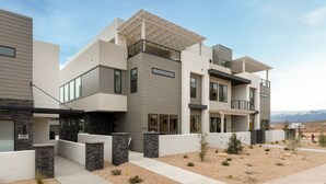 A modern multi-story residential building with a flat roof, large windows, and a landscaped front yard. - The Solace at Desert Color (by Ember Stays) (St. George)