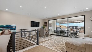 A modern apartment with a balcony, a dining area, and a living room with a large window. - The Solace at Desert Color (by Ember Stays) (St. George)