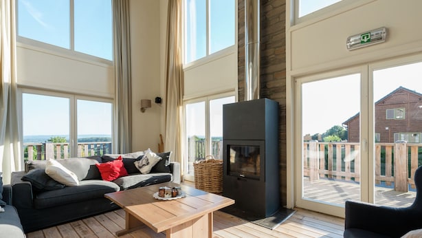 A spacious living area with a fireplace, large windows, and a view of the outdoors.