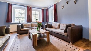 A living room with two sofas, a coffee table, and a window with curtains.