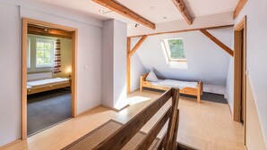 A room with a sloped ceiling, wooden beams, a window, and a bed.
