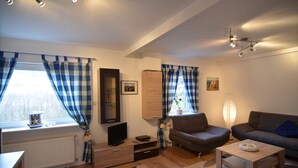 A modern living room with a sofa, a coffee table, a TV, and a fireplace. - Chalet im Sauerland nahe Skigebiet Winterberg (Elpe)