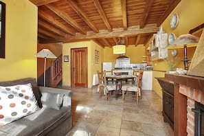 Una sala de estar acogedora con sofá, una mesa de comedor con sillas, una zona de cocina con estufa y un techo de madera.