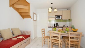 A compact living space with a kitchenette, a dining area, and a sofa with cushions. - Tranquil Escape with Pool (Rignac)