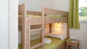 A bunk bed with a ladder, a bedside table with a lamp, and a window with curtains. - Apartment in Rignac near Lake Peyrade (Rignac)