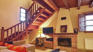 A cozy living room with a wooden staircase, a fireplace, a television, and a comfortable sofa. - Cozy Cottage with Pool & Terrace (Nava)