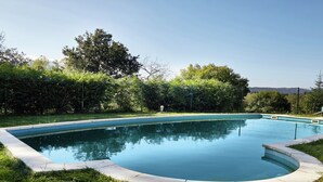 A rectangular swimming pool with a curved edge, surrounded by grass and trees. - Cozy Cottage with Pool & Terrace (Nava)
