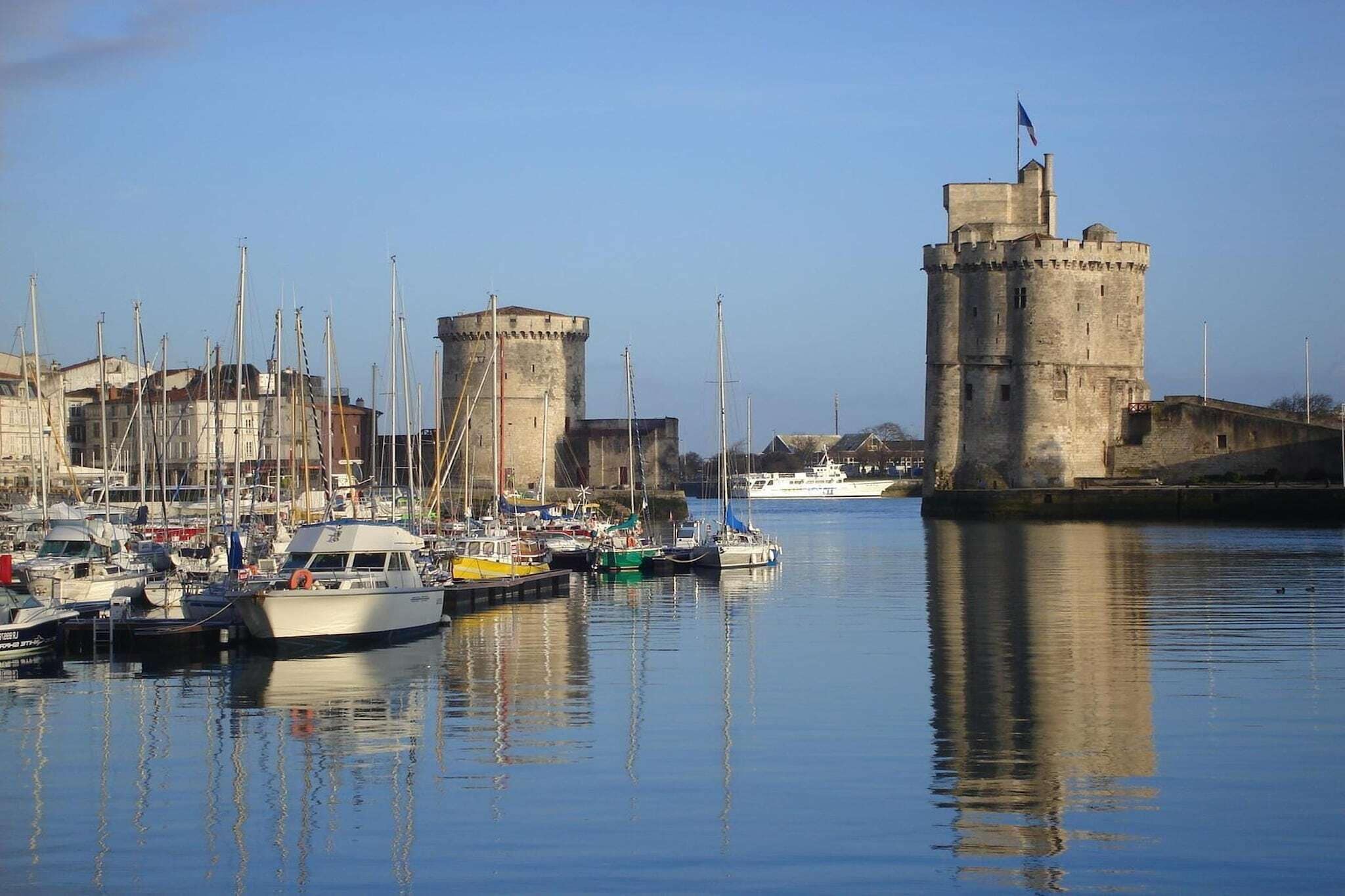A harbor with boats docked, a castle, and a clear sky.