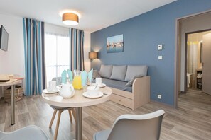 Ein stilvolles Wohnzimmer mit Sofa, einem Esstisch, der mit Tellern, Tassen und einer Karaffe gedeckt ist, und einer Lampe.