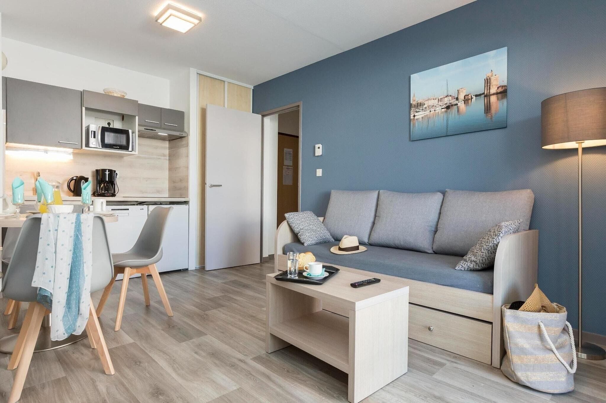 A modern living room with a sofa, coffee table, and a dining area with chairs and a table.