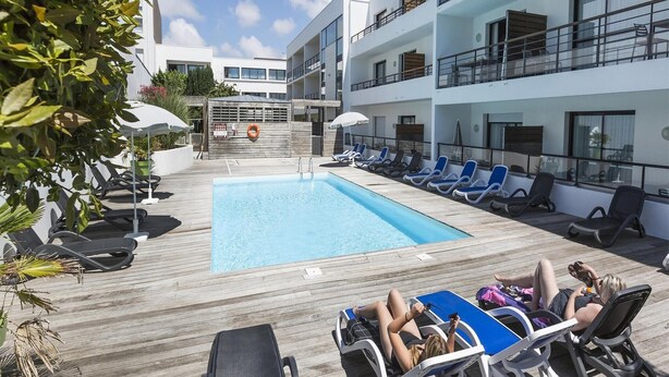 A poolside area with lounge chairs and a swimming pool, surrounded by multi-story buildings. - Apartment in La Rochelle near the Beach (La Rochelle)