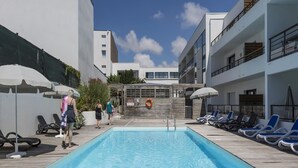 A swimming pool with lounge chairs and umbrellas, surrounded by buildings. - Apartment in La Rochelle near the Beach (La Rochelle)