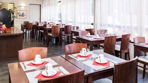 A hotel dining area with wooden tables and chairs, arranged in rows, with a reception desk in the background. - Apartment in La Rochelle near the Beach (La Rochelle)