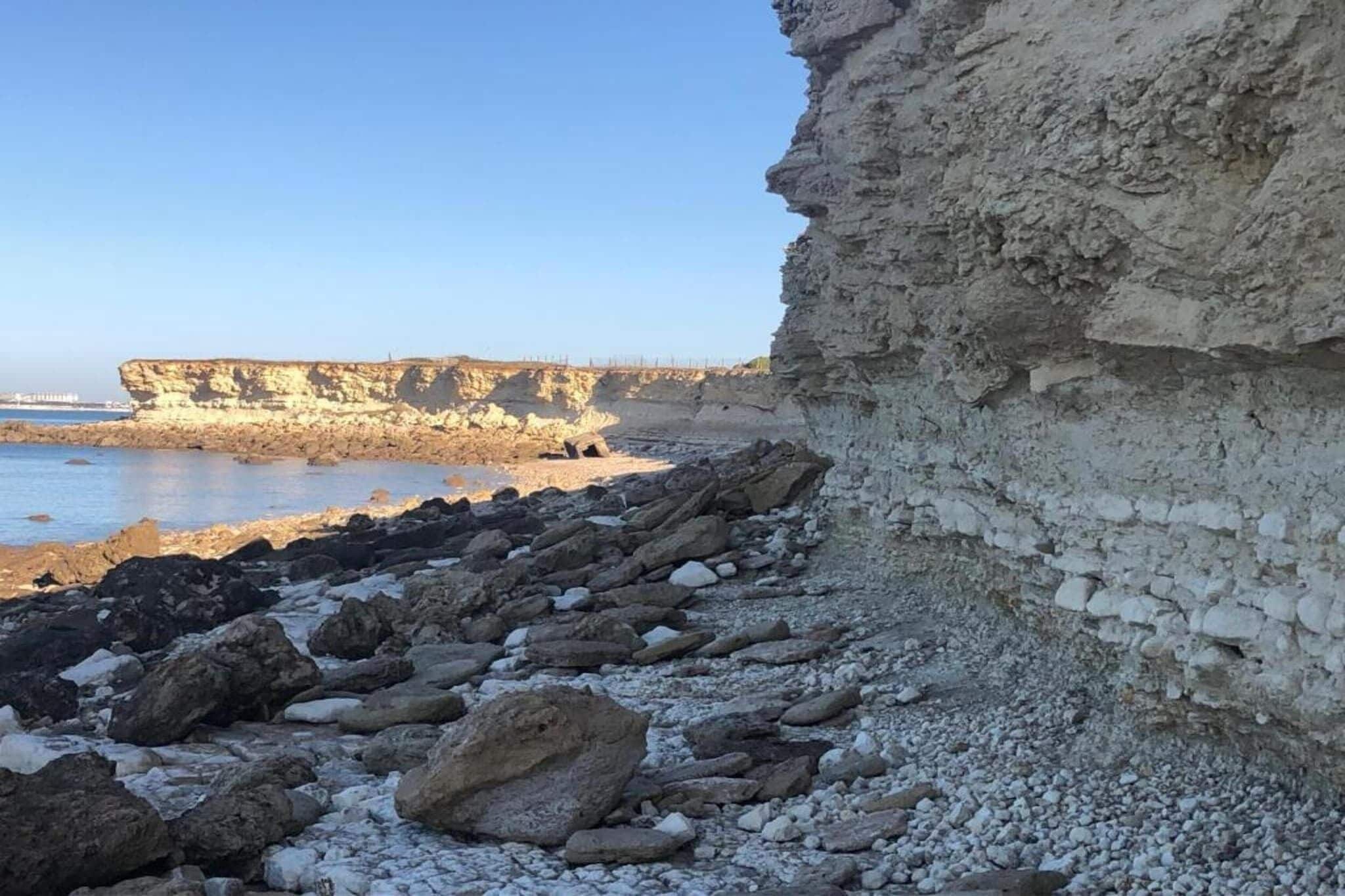 A coastal landscape with rocky terrain and cliffs.