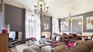 A modern living room with a brown leather sofa, a wooden coffee table, and a television on a stand.