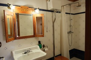 A bathroom with a wooden vanity, a sink, a mirror, a shower, and patterned tiles.