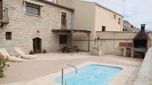 Un bâtiment en pierre doté d’une piscine, d’un espace extérieur aménagé et d’un coin barbecue.
