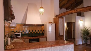 Une cuisine équipée d’un four à micro-ondes, d’un évier et d’un réfrigérateur. On y trouve également un luminaire suspendu et une poutre en bois au plafond.
