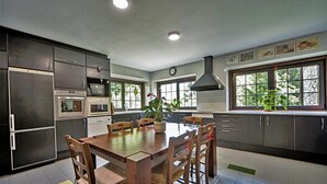 Una cocina moderna con armarios oscuros, una mesa de comedor de madera y un ventanal grande.