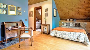 Un dormitorio con techo de madera, una cama con ropa de cama floral, un aparador y una silla.