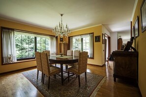 Une salle à manger avec une table ronde, des chaises, un lustre et de grandes fenêtres.
