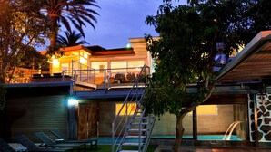 Uma casa moderna com varanda, piscina e escadaria que leva a um segundo andar.