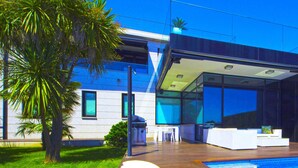 A modern house with a pool, outdoor seating, and a large glass window.