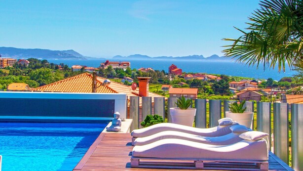 A poolside area with lounge chairs and a view of the sea.