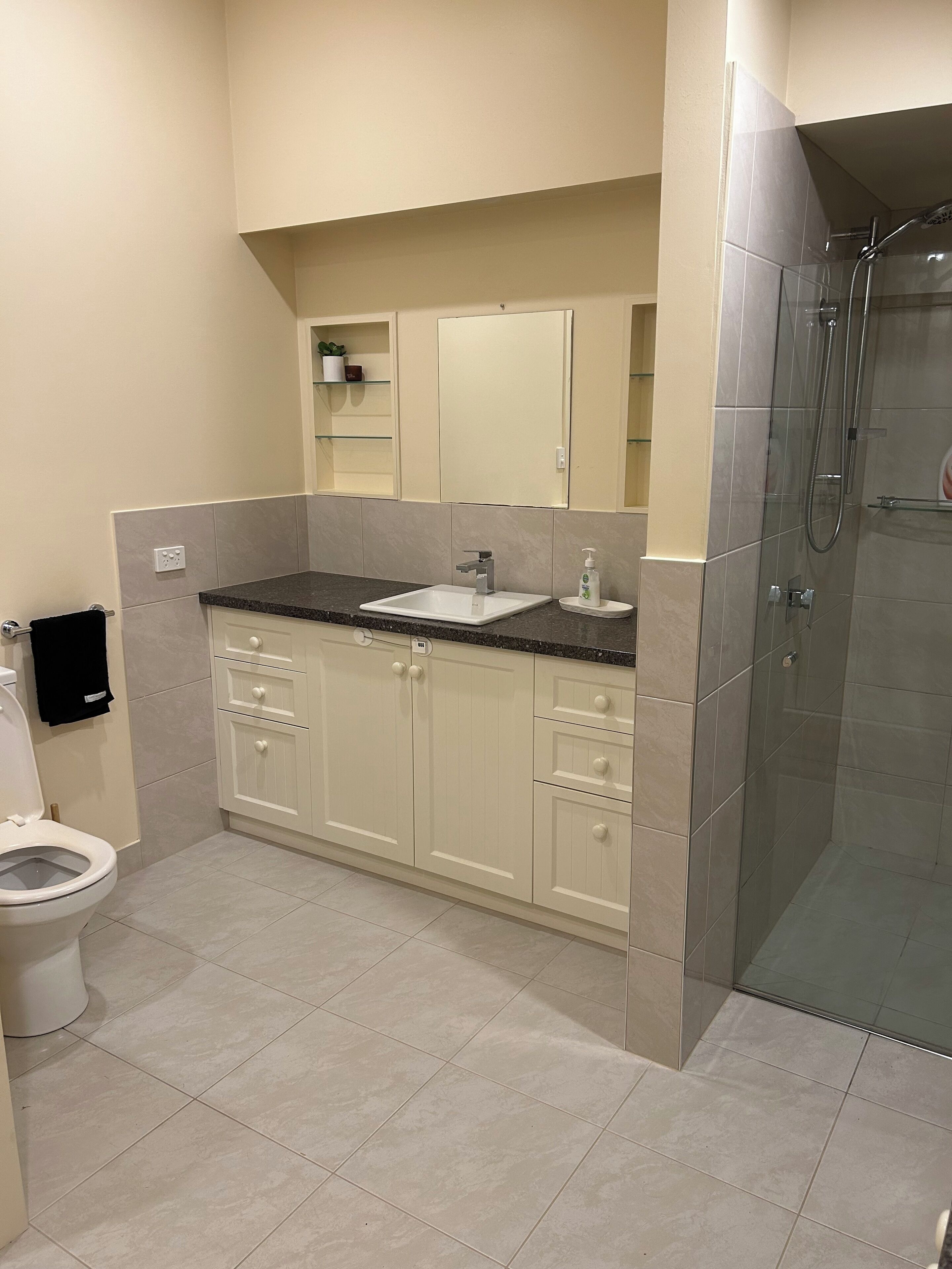 A modern bathroom with a white sink, vanity, and shower.