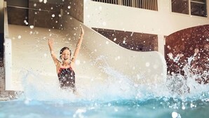 Eine Person im Schwimmbecken, umgeben von spritzendem Wasser.