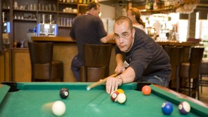 Ein Billardtisch mit Kugeln, eine Bar und Sitzgelegenheiten in einem Raum.