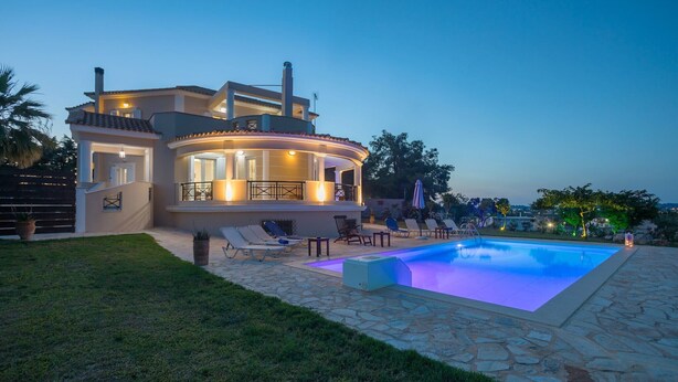 Ein modernes Haus mit Swimmingpool, Sitzgelegenheiten im Freien und einer gut beleuchteten Terrasse.