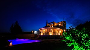 Ein großes, rundes Haus mit Balkon und Pool im Abenddämmerung.