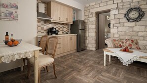 Une cuisine de taille réduite, dotée de meubles en bois, d’un réfrigérateur et d’un coin repas avec une table et des chaises.
