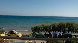 Une vue sur la côte, avec une voiture jaune garée sur la plage, une voiture verte et un drapeau.