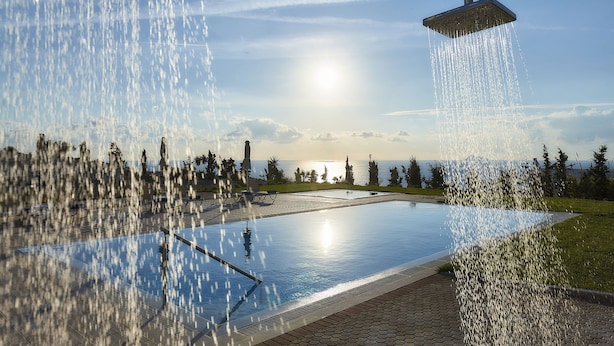 Une piscine dotée d’une douche, entourée d’une zone dallée et offrant une vue sur la mer.