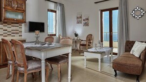A spacious living room with a dining area, a TV mounted on the wall, and a balcony with a view. - Villa in Kamilari near Kid-Friendly Beach (Kamilari)
