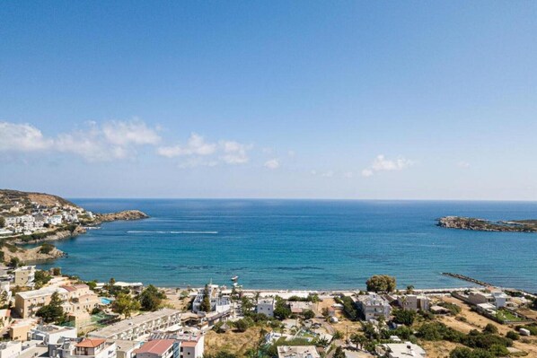 A coastal town with buildings along the shoreline, a clear blue sky, and calm sea.