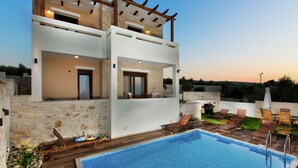 Une maison moderne à deux étages dotée d’une piscine, d’un espace salon extérieur et d’une pergola.