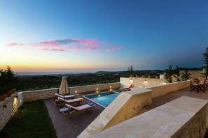 A rooftop pool area with lounge chairs, a small pool, and a view of the landscape.