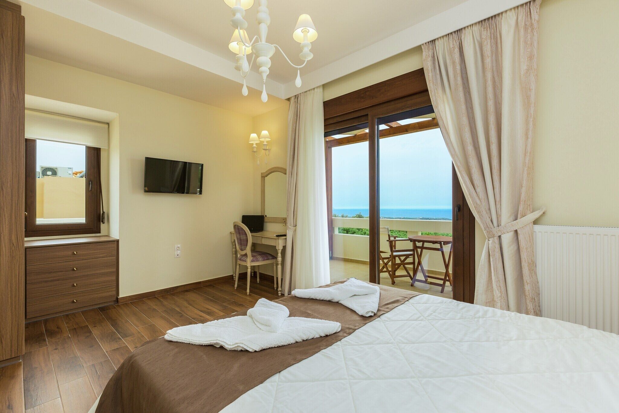 Habitación de hotel con cama, escritorio, silla, televisor y vista al mar.