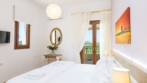 Et hotelværelse med seng, fjernsyn, spejl, et vindue med gardiner og et billede på væggen.