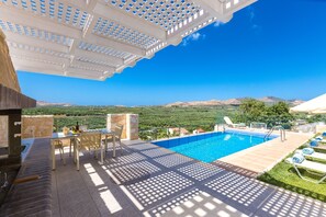 A pool area with a view of the landscape, a table with chairs, and a pergola structure. - Villa in Crete with Private Pool & BBQ (Achlades)