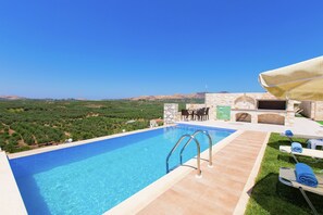Una piscina con vistas despejadas del paisaje circundante, una estructura de piedra y mobiliario exterior.