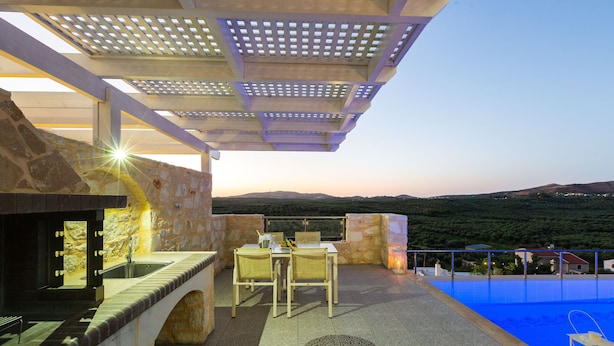 An outdoor patio with a pool, stone walls, and a table with chairs. - Villa in Crete with Private Pool & Beaches Nearby (Achlades)