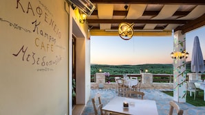 An outdoor café with stone flooring, wooden furniture, and a view of the countryside. - Villa in Crete with Private Pool & Beaches Nearby (Achlades)