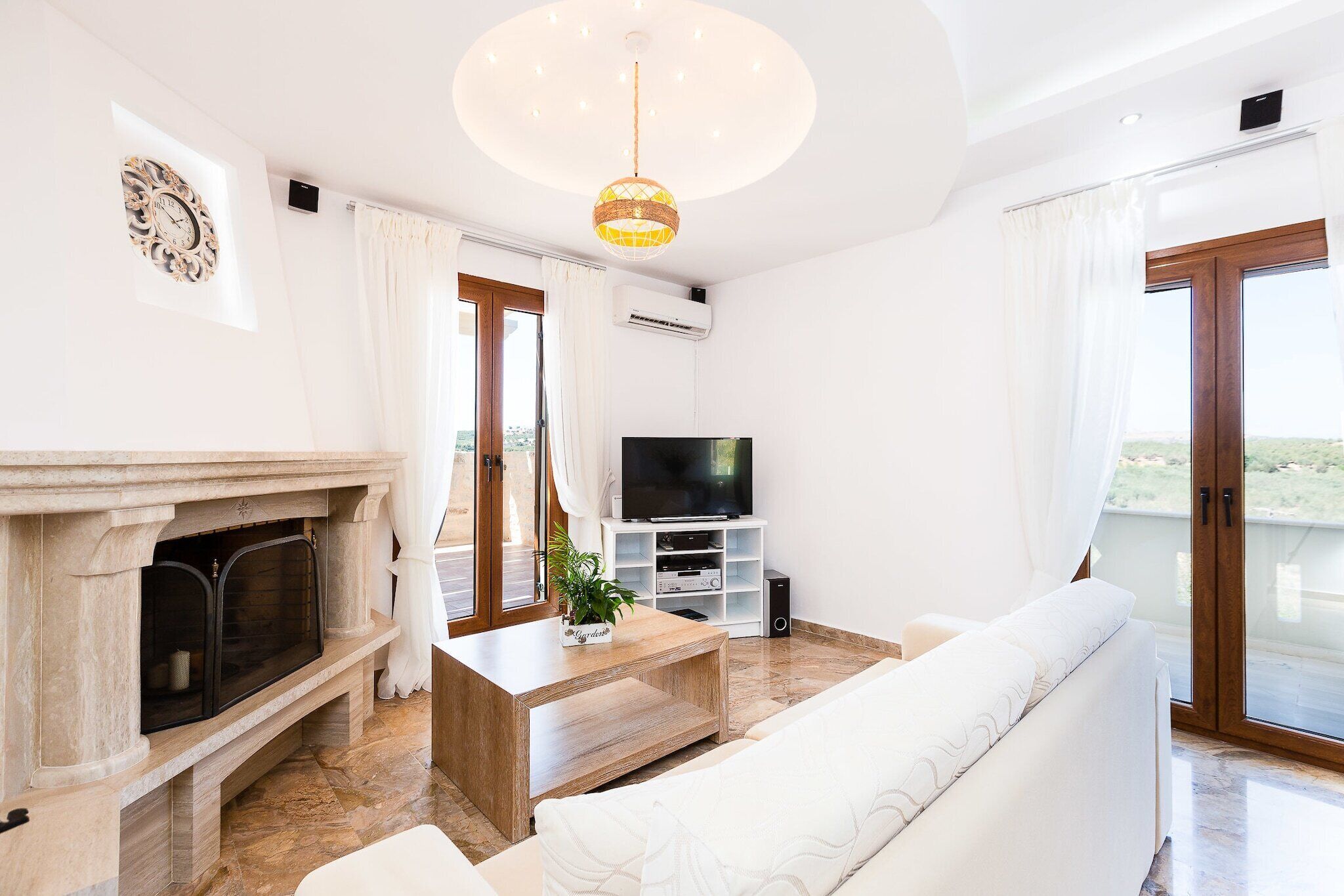 A living room with a fireplace, a television, a sofa, and a ceiling light.